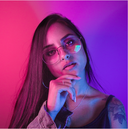 A tech creator portrait lit in neon pink and blue.